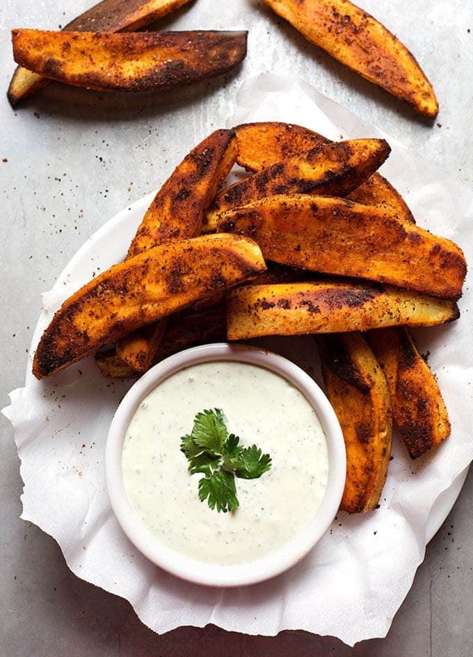 Plate of seasoned sweet potato fries with a small bowl of dip
