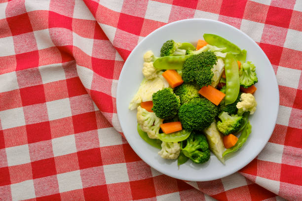 Plate of mixed steamed vegetables: broccoli, cauliflower, carrots, snap peas